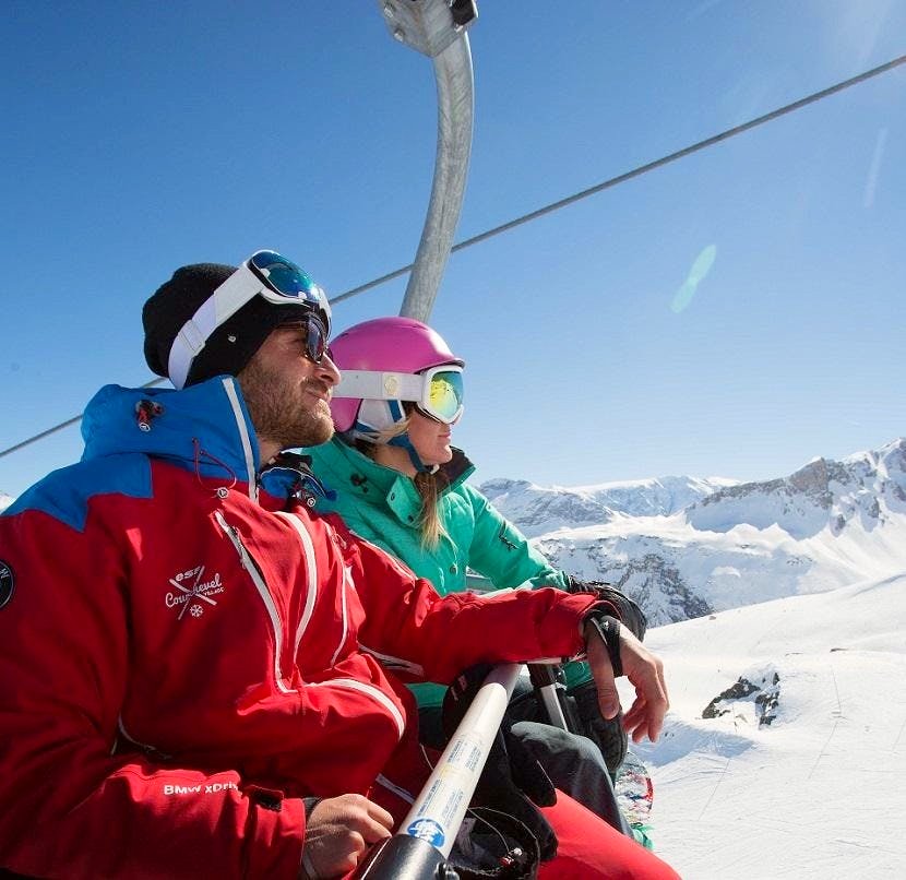 Un moniteur de snowboard et son élève sont assis dans un téléski aux 3 Vallées.