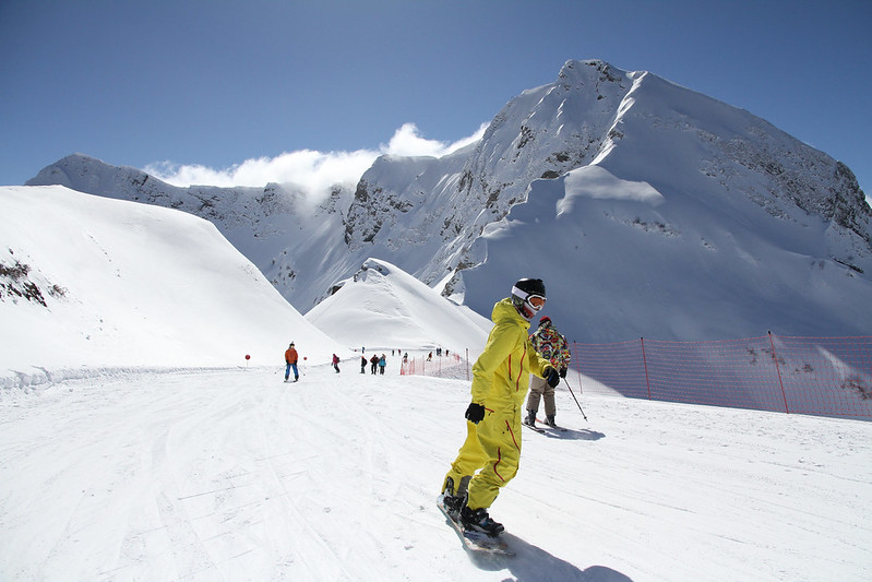 Een snowboarder gaat de piste af nadat hij heeft leren snowboarden tijdens lessen met materiaalverhuur.