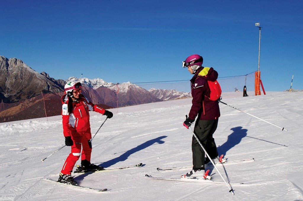 Maestra di sci con adulto principiante durante lezione privata di sci per adulti a Monte Pora.
