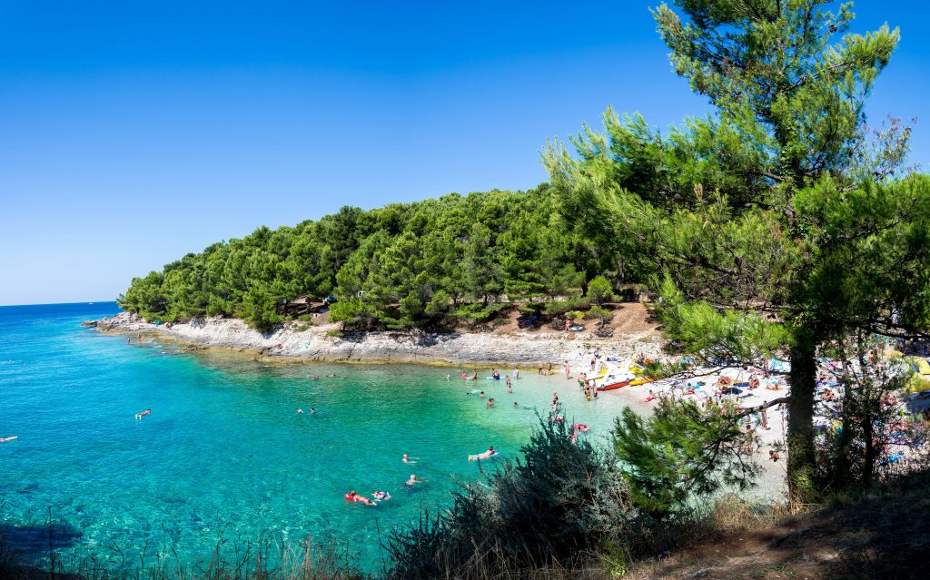 A beautiful secluded beach in Pula with people enjoying water sports activities.
