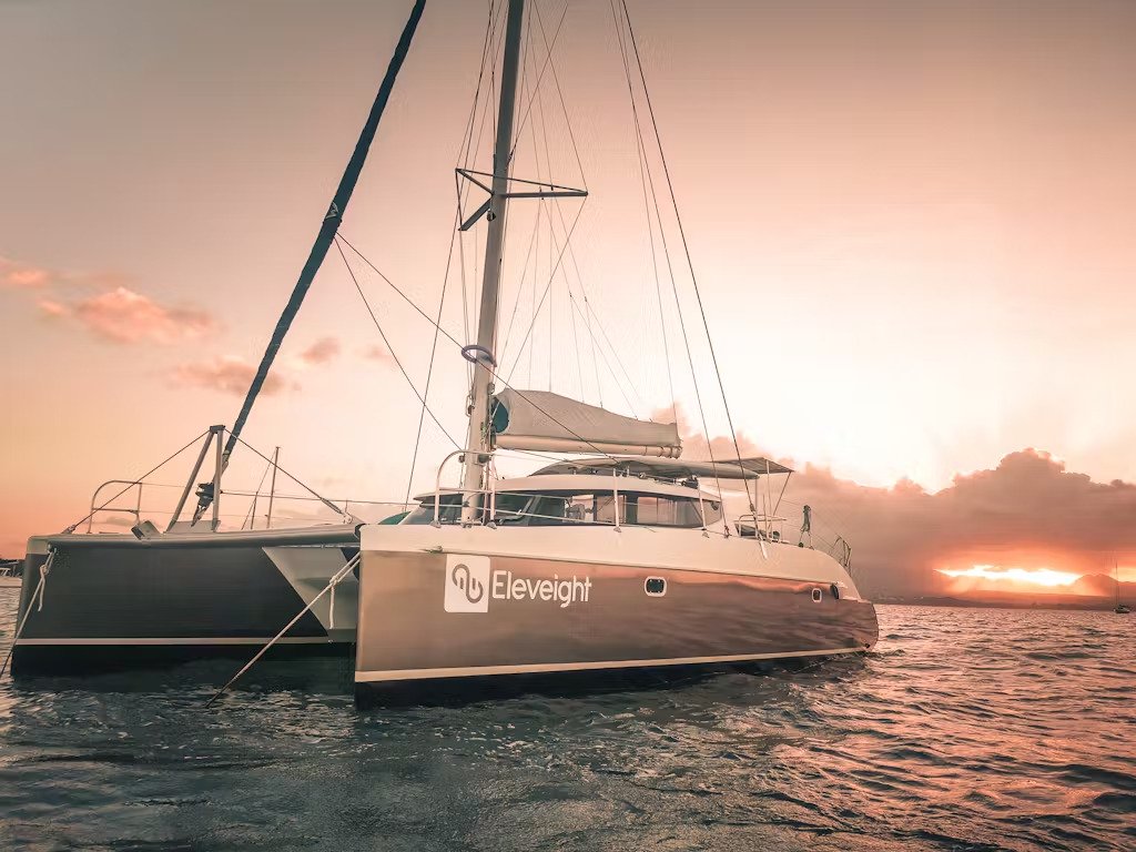 A catamaran sailing peacefully in the ocean during sunset, surrounded by stunning colors in the sky - © Azimut Id'Ile.