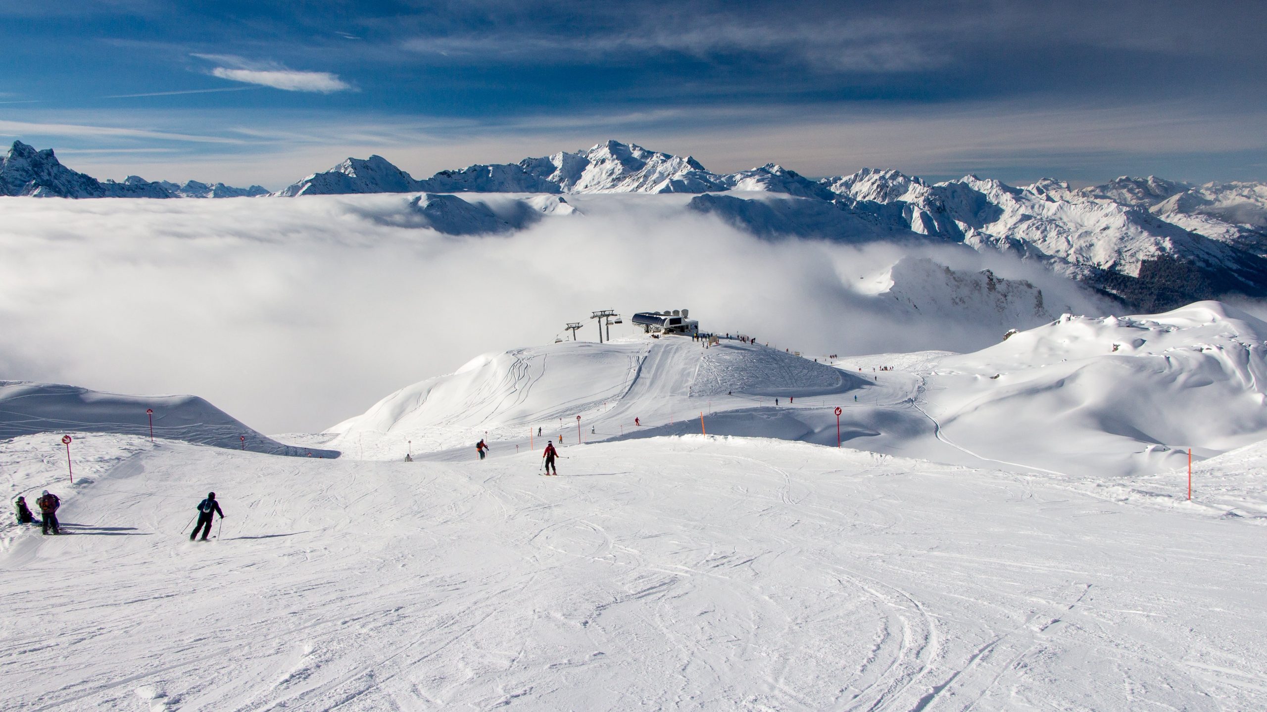 Das Skigebiet Ski Arlberg an einem sonnigen Tag, in der Nähe von St. Anton, mit Skifahrern auf der Piste.