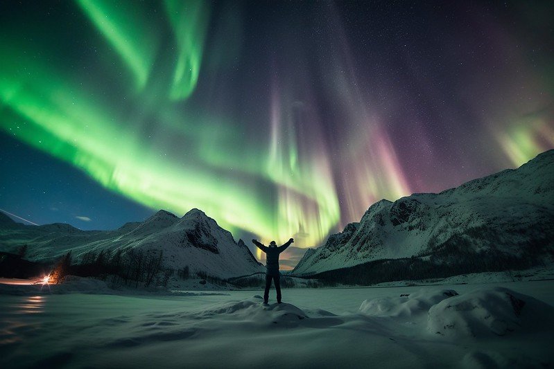 A person is admiring the wonderful and magical view of the Northern Lights dancing in the sky.
