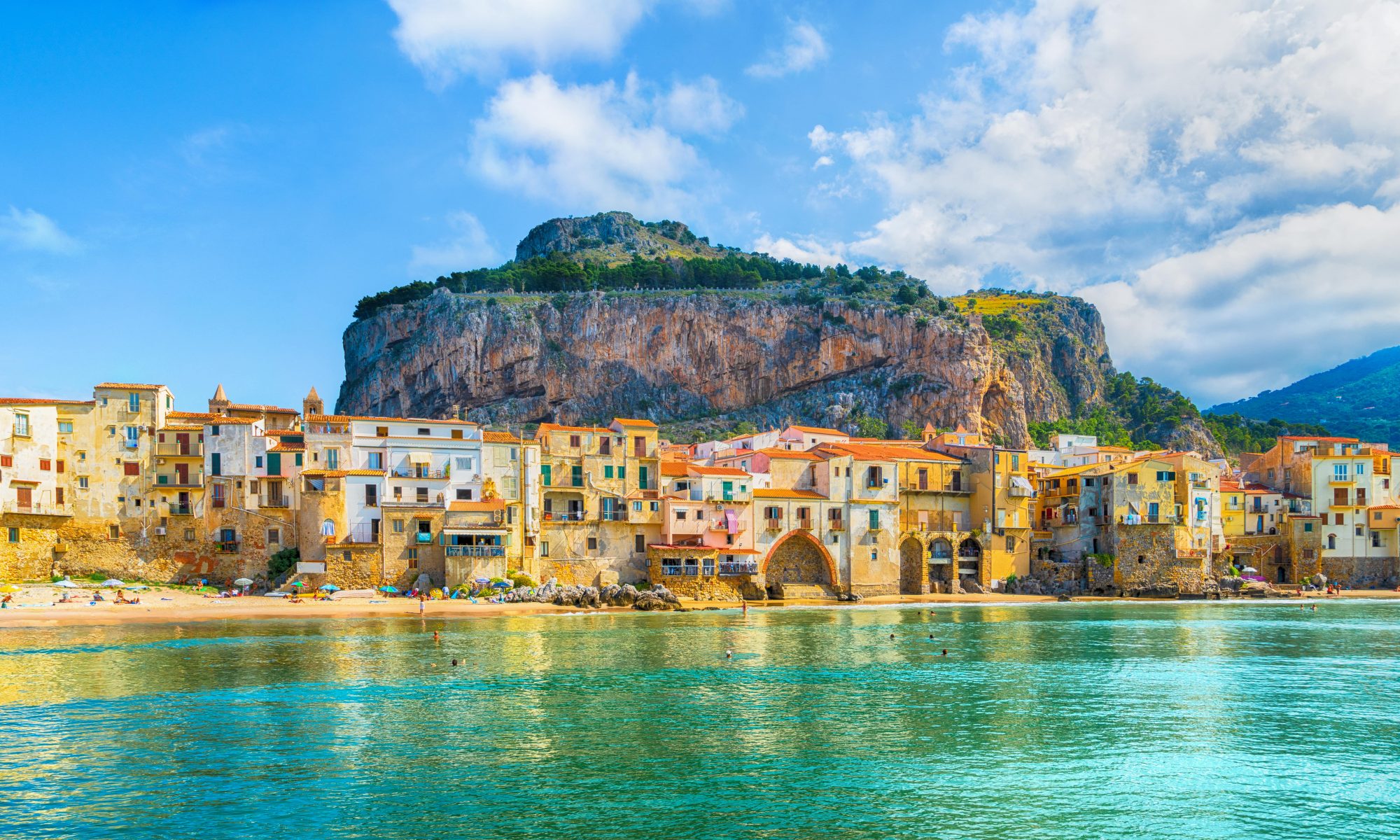 Cefalù Beach in Sicily, with La Rocca Mountain in the background.