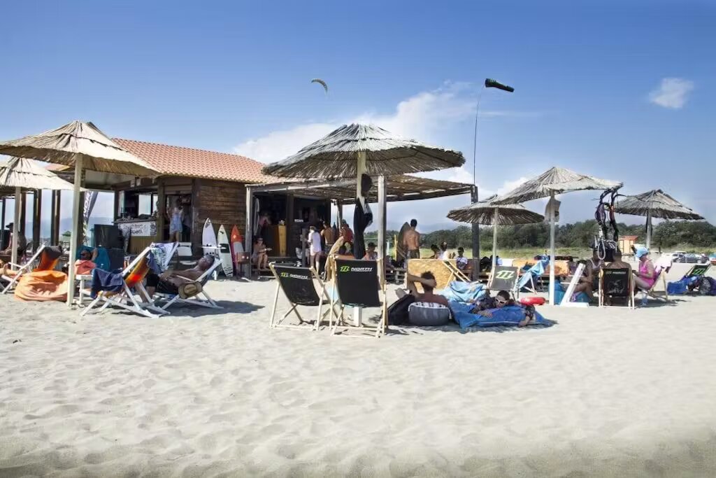 People enjoying Ulcinj's bright sandy beach and lounging in sun chairs.